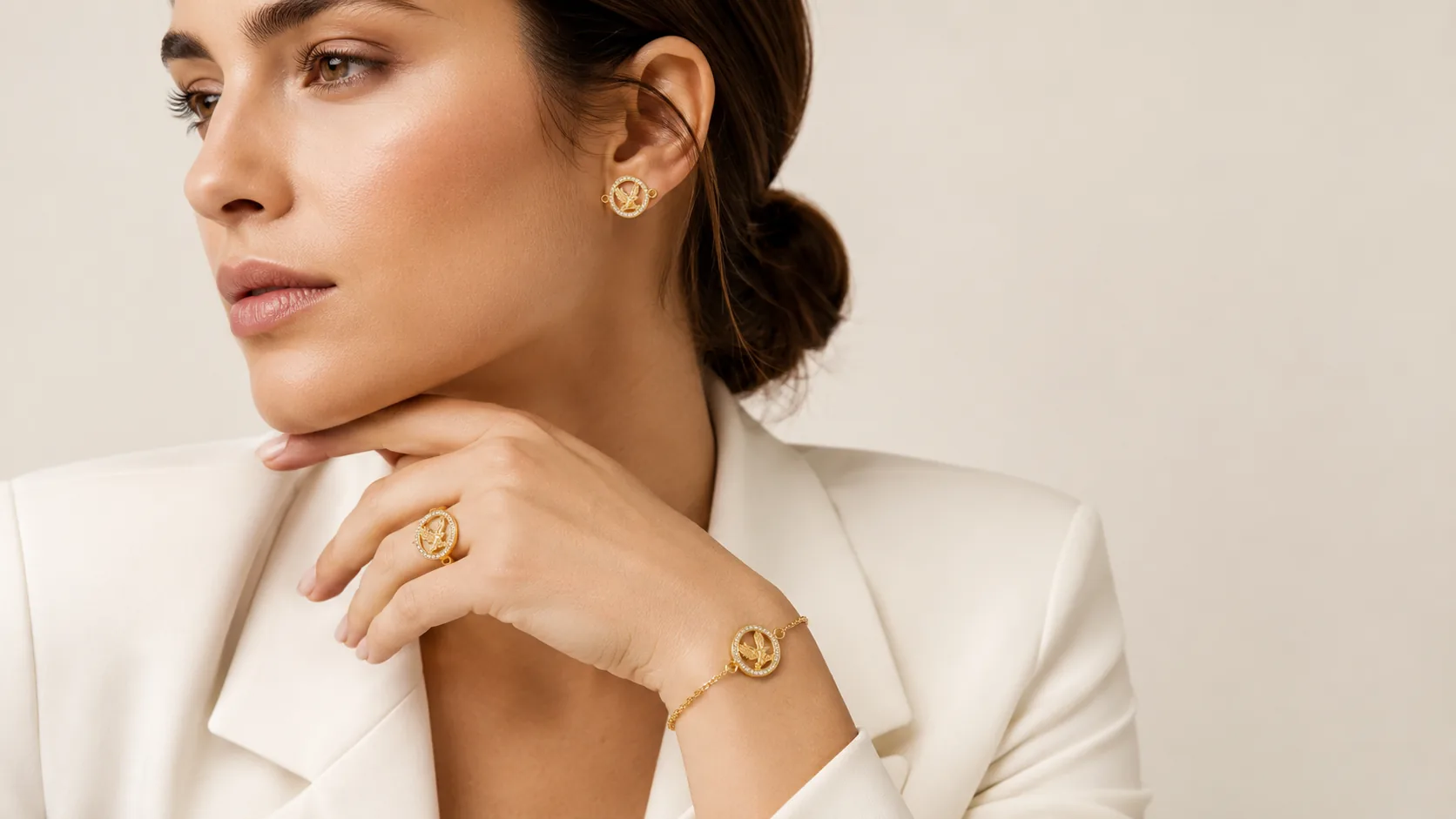 Mujer con blazer blanco lleva joyas con el símbolo del águila en oro