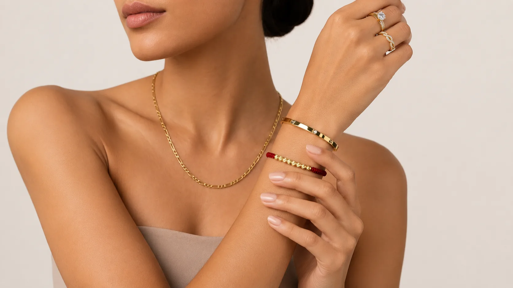 Cadena, brazalete y anillos de oro sobre la piel